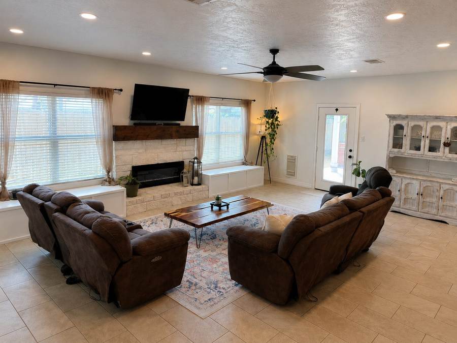 The renovated living room: stone fireplace with a wood mantel, fresh paint, warm lighting and new furniture